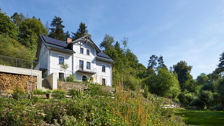 Das Gästehaus Tauhaus in Manetin Tschechien, auf einem begrünten Hügel mit Gartenanlage. | © Clocal Consulting